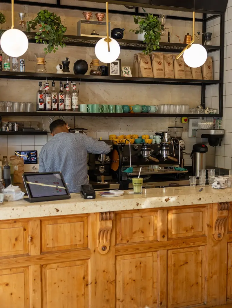Le bar en bois et la machine à espresso, avec un barista au travail