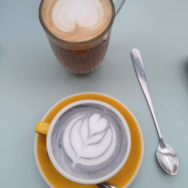 Vanilla charcoal latte gris avec latte art dans une tasse jaune