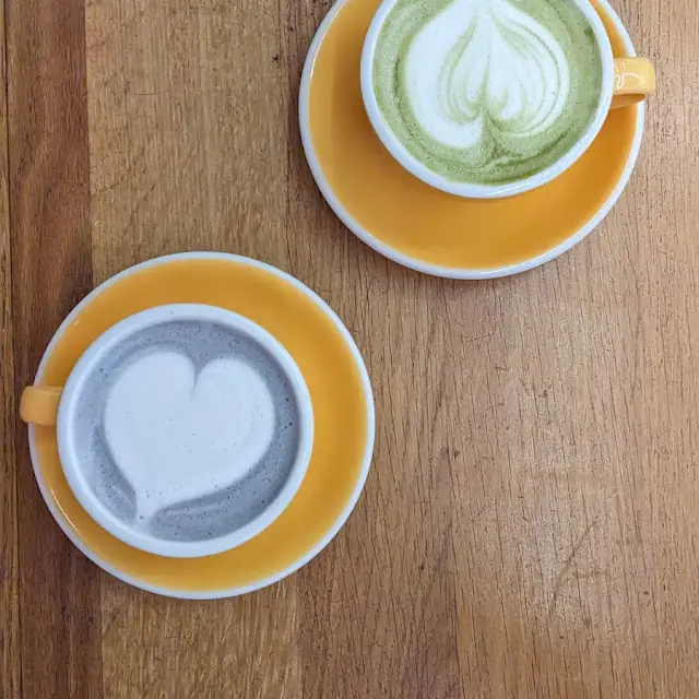 Green matcha latte et charcoal latte sur une table en bois