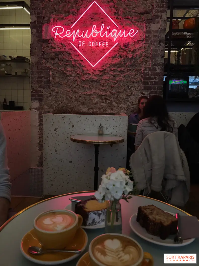 Le néon rose « Republique of coffee » au-dessus d’une table du café
