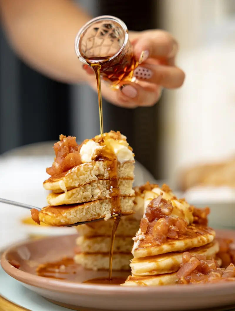 Sirop d’érable versé sur des pancakes à la pomme et à la cannelle